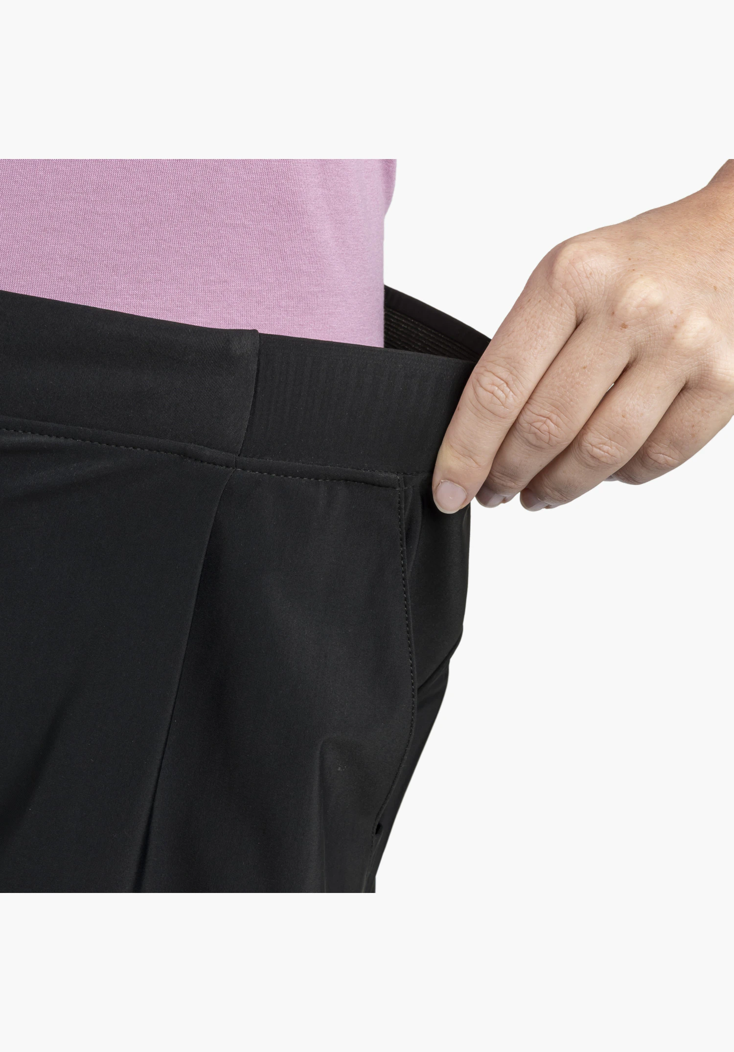 Jersey Pants Style Calmay WMN, une main étire la taille élastique noire pour montrer la souplesse de la matière, gros plan sur fond blanc/neutre.