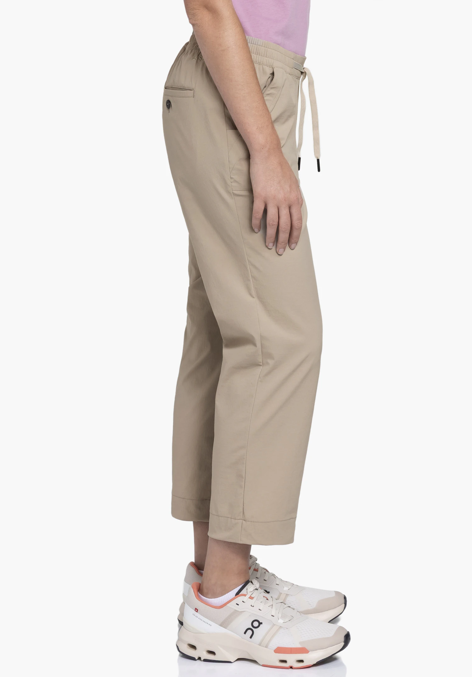 Pants Rangun L worn by a model standing sideways. The beige trousers feature an elasticated waistband with a drawstring and a subtle Schöffel-Logo below the waist, presented against a neutral background.