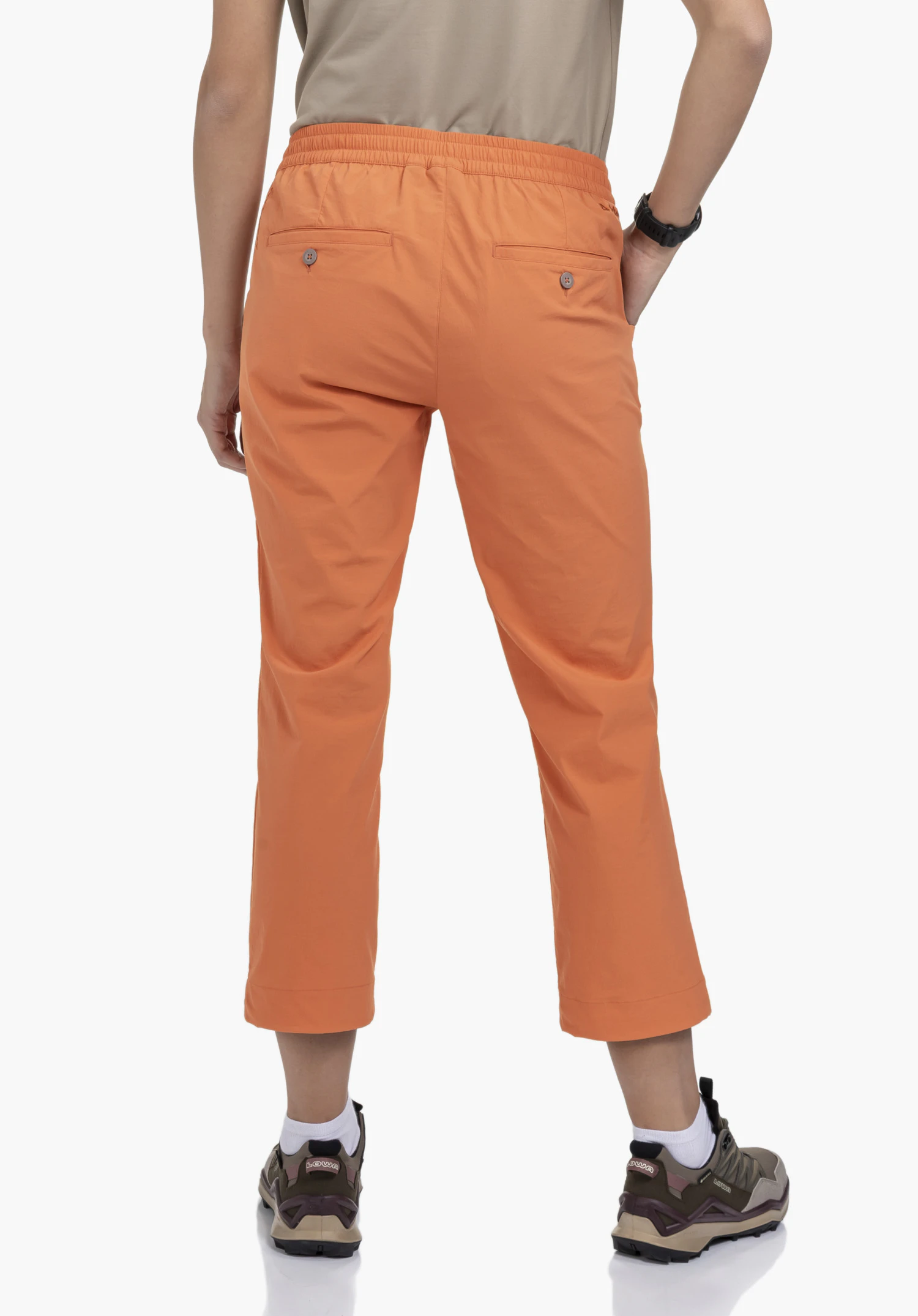 Pants Rangun L en orange, vue de dos portée par un mannequin sur fond neutre, mettant en évidence la taille élastiquée, les poches arrière et le logo Schöffel.