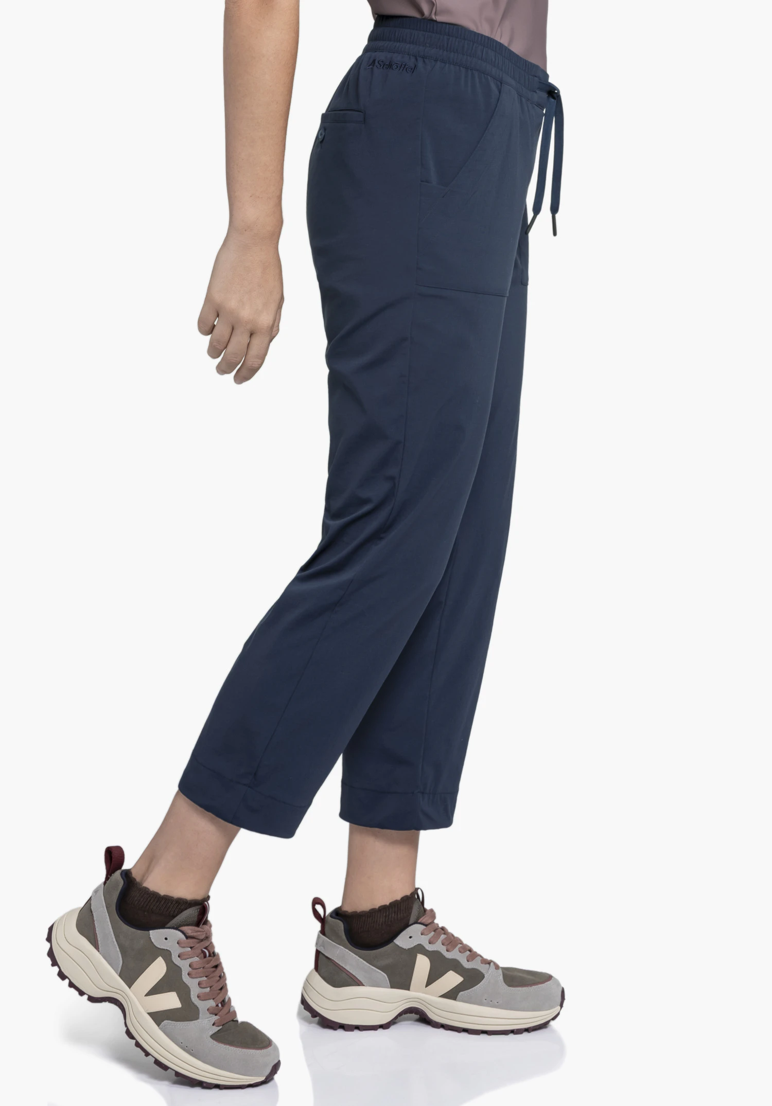 Pants Rangun L in blue. A model stands sideways showcasing the trousers with the Schöffel logo visible on the waistband against a neutral background.