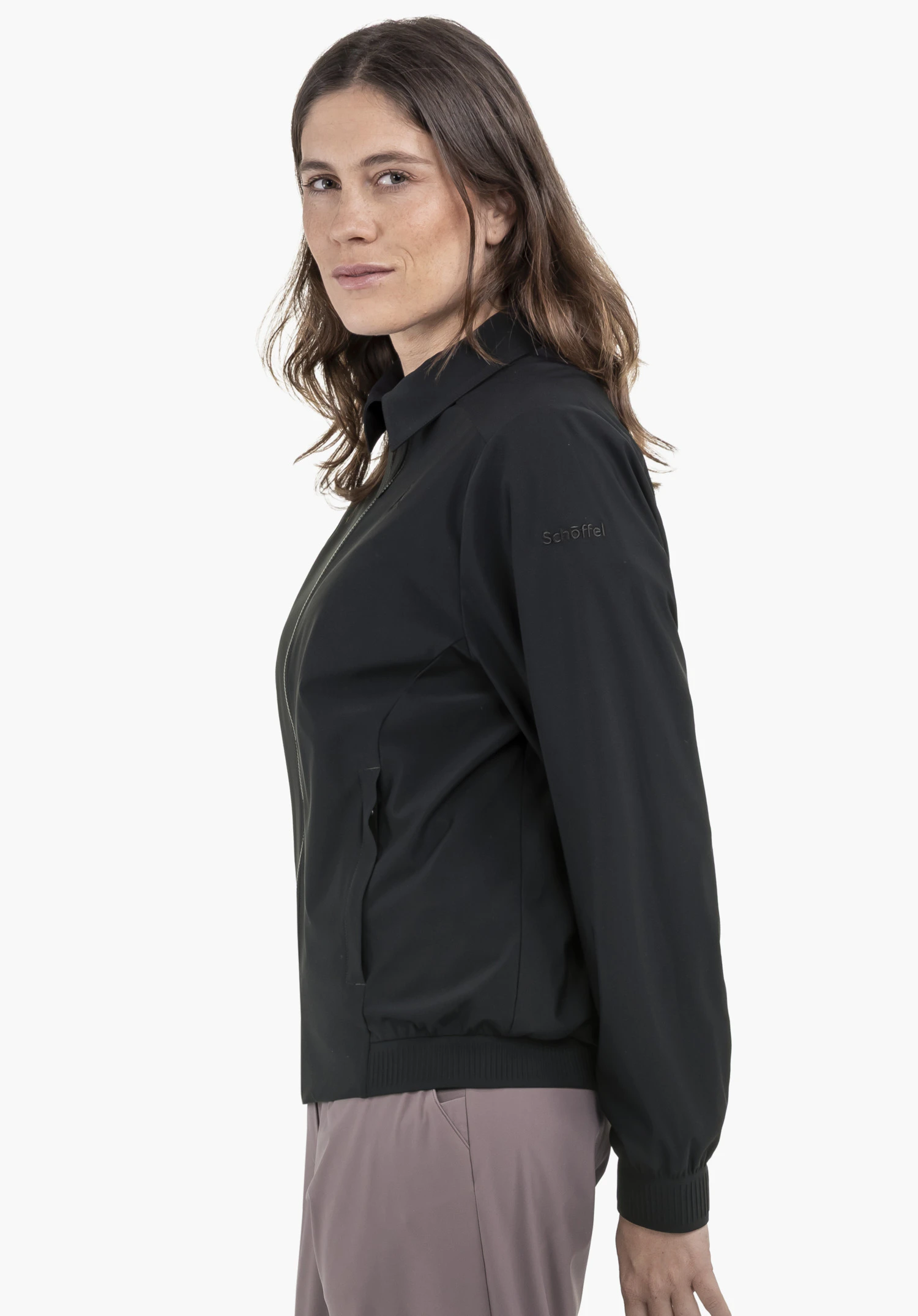 Jersey Jk Style Calmay WMN : Un mannequin se tient de profil et présente la veste en noir. Le logo Schöffel est bien visible sur la manche, photographié devant un fond neutre.
