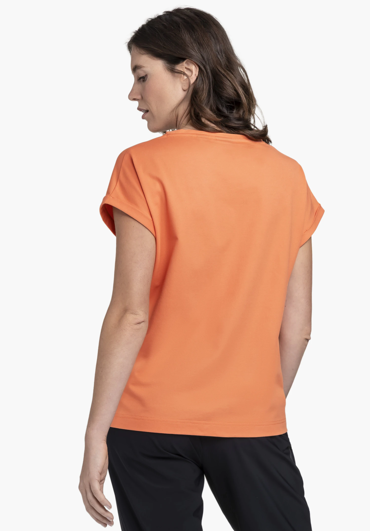 T Shirt Style Serenio WMN in vibrant orange shown from the back. The model is standing in front of a neutral background and looking slightly to the side, highlighting the comfortable fit of the shirt.