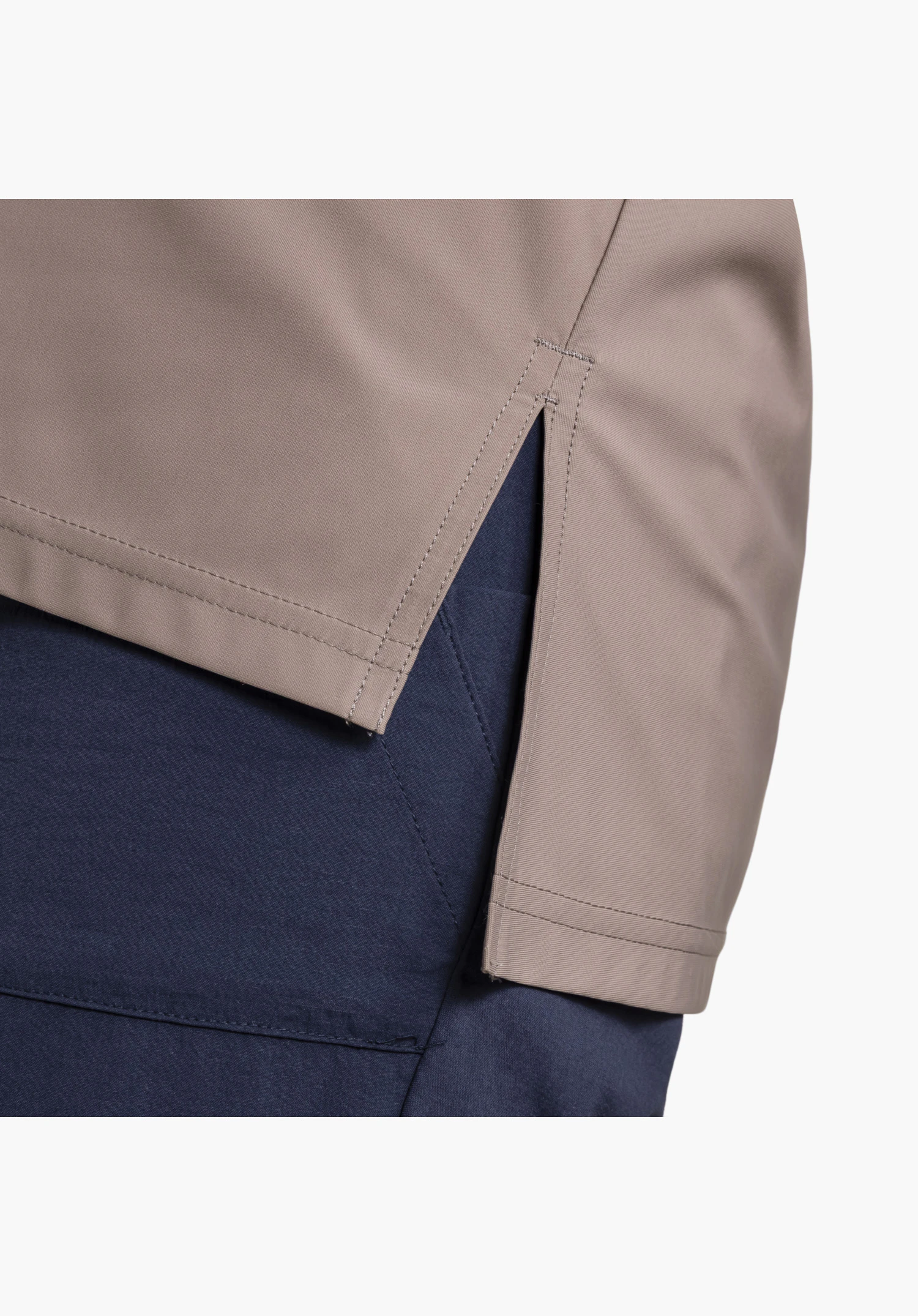 Jersey Polo Style Calmay WMN in brown, focusing on the side slit at the hem worn over dark blue trousers, close-up against a white/neutral background.
