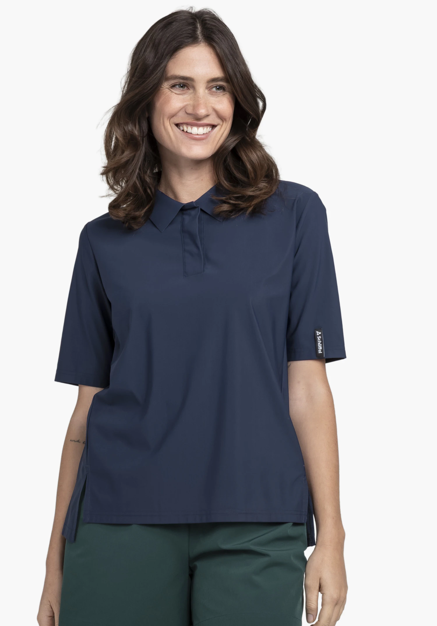 Jersey Polo Style Calmay WMN in Blau. Das Model steht frontal und trägt das Kurzarm-Poloshirt mit Kragen. Am linken Ärmel ist ein kleines Schöffel-Logo sichtbar, präsentiert vor einem neutralen Hintergrund.