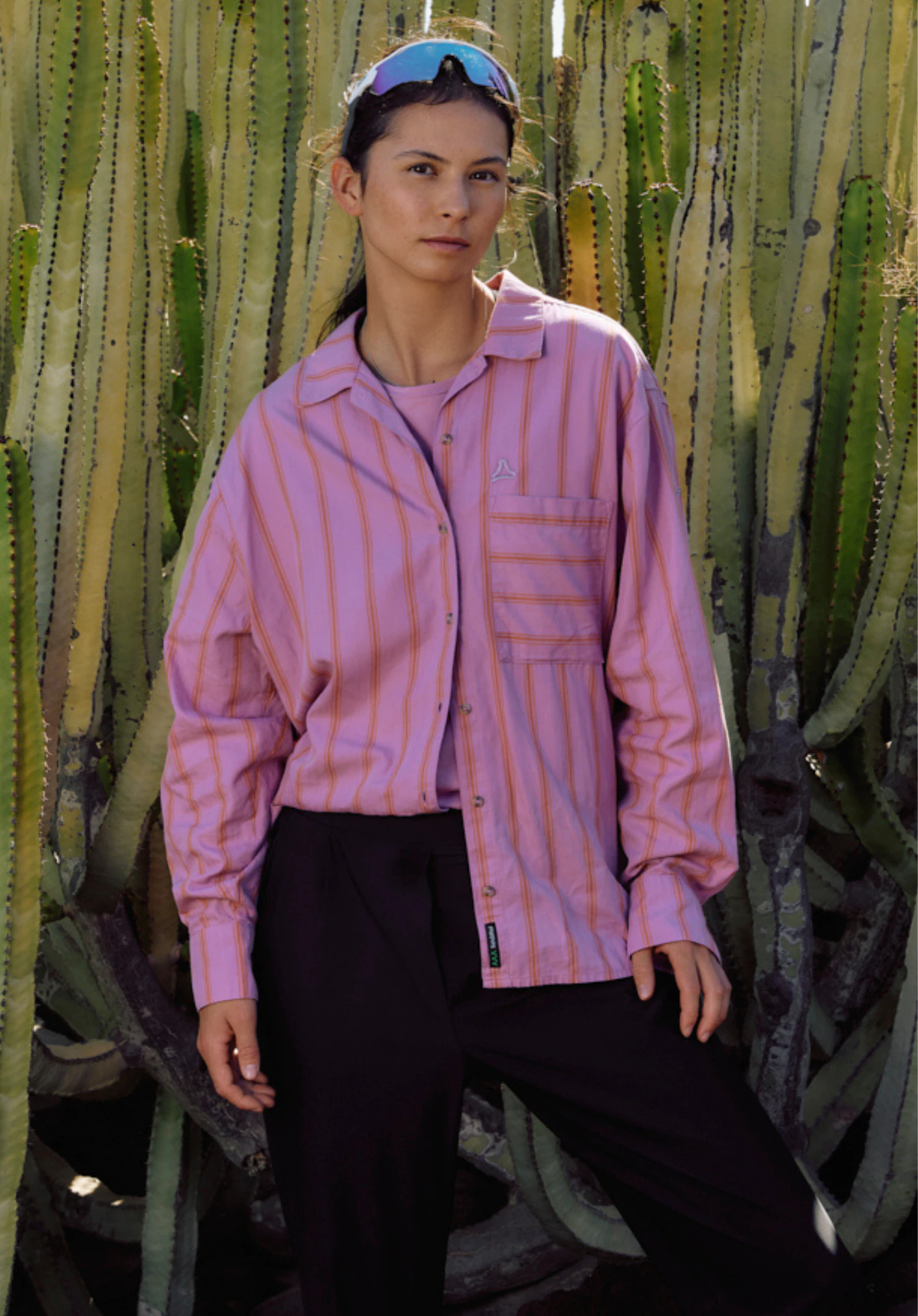 Blouse Style Chanduy WMN portée par un mannequin debout de face et regardant l'objectif. Le chemisier rose à manches longues présente un motif à rayures et une poche poitrine au-dessus de laquelle le logo Schöffel est visible, photographié sur un fond neutre.