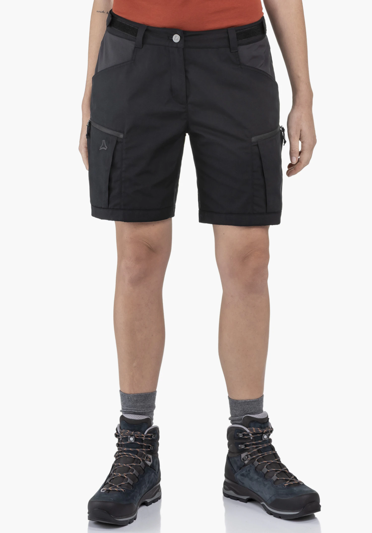 Shorts Style Maghera WMN getragen von einem Model in der Vorderansicht. Die kurze Hose in der Farbe Schwarz zeigt das Schöffel-Logo auf der rechten Beintasche. Das Model steht aufrecht vor einem neutralen Hintergrund.