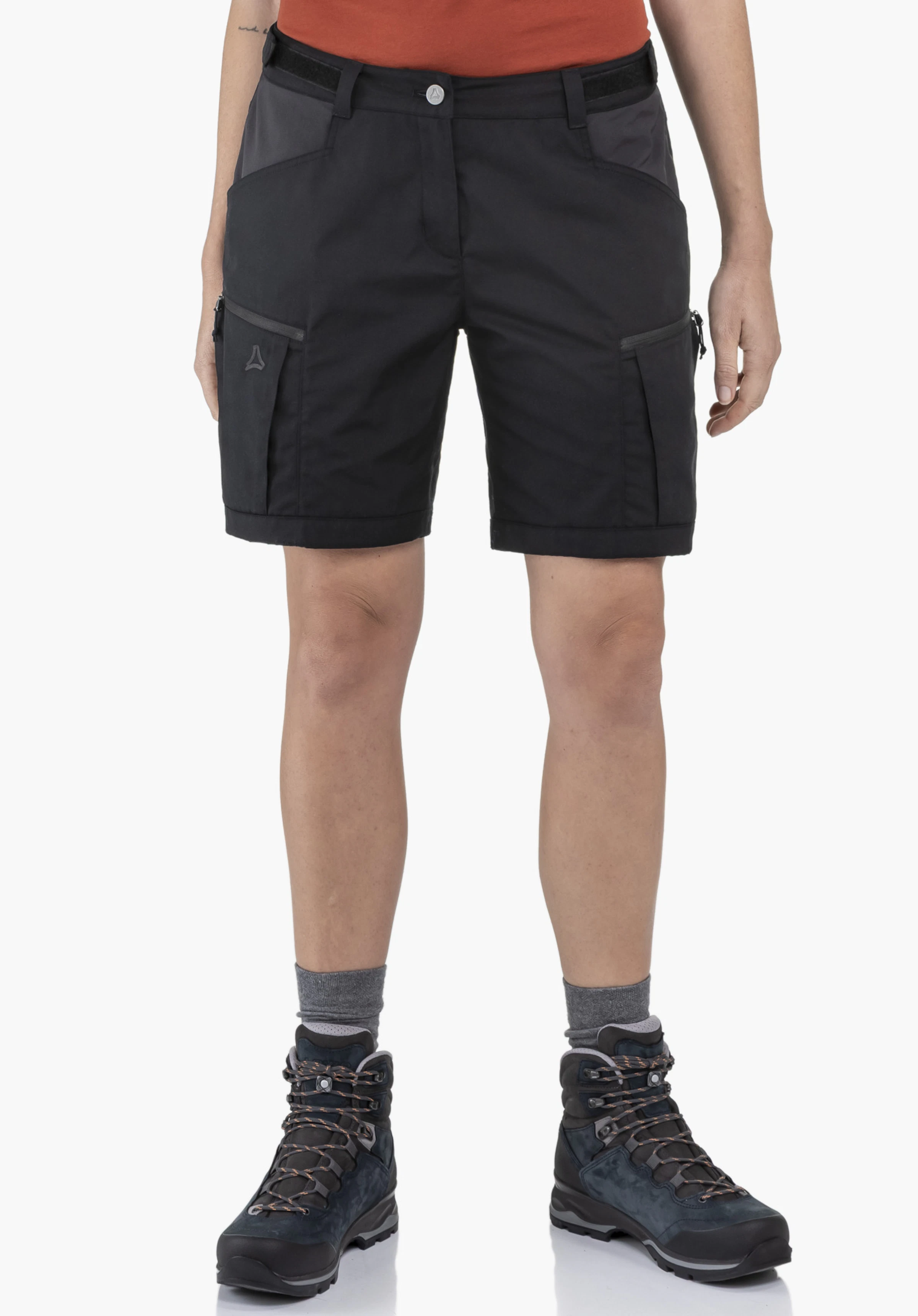 Shorts Style Maghera WMN porté par un mannequin en vue de face. Le short de couleur noire présente le logo Schöffel sur la poche de la jambe droite. Le mannequin se tient droit devant un fond neutre.