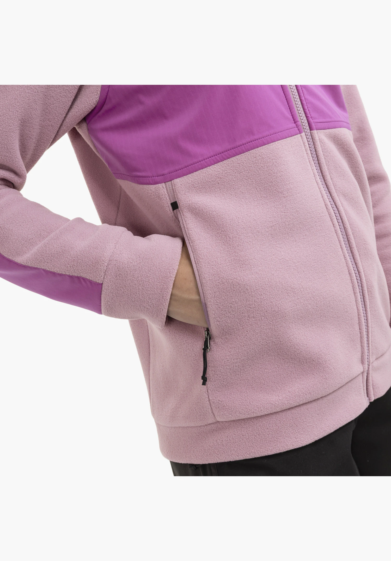 Fleece Jk Style Maghera WMN showing the soft pink fleece texture, the smooth contrasting material on the chest and sleeve, and the open side zip pocket with a black pull cord. Close-up against a white/neutral background.