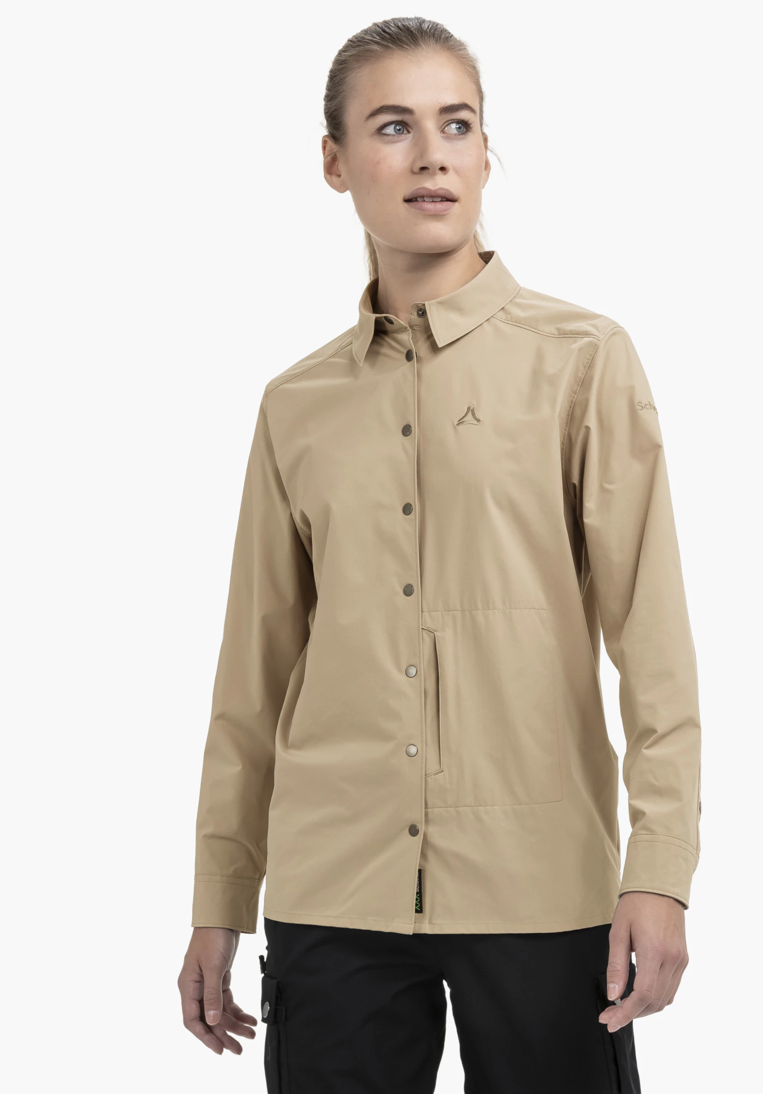 Blouse Style Maghera WMN en beige. La vue de face montre un mannequin sur un fond neutre portant la chemise avec un col classique et une patte de boutonnage sur toute la longueur. Le logo Schöffel de haute qualité est discrètement brodé sur la poitrine.