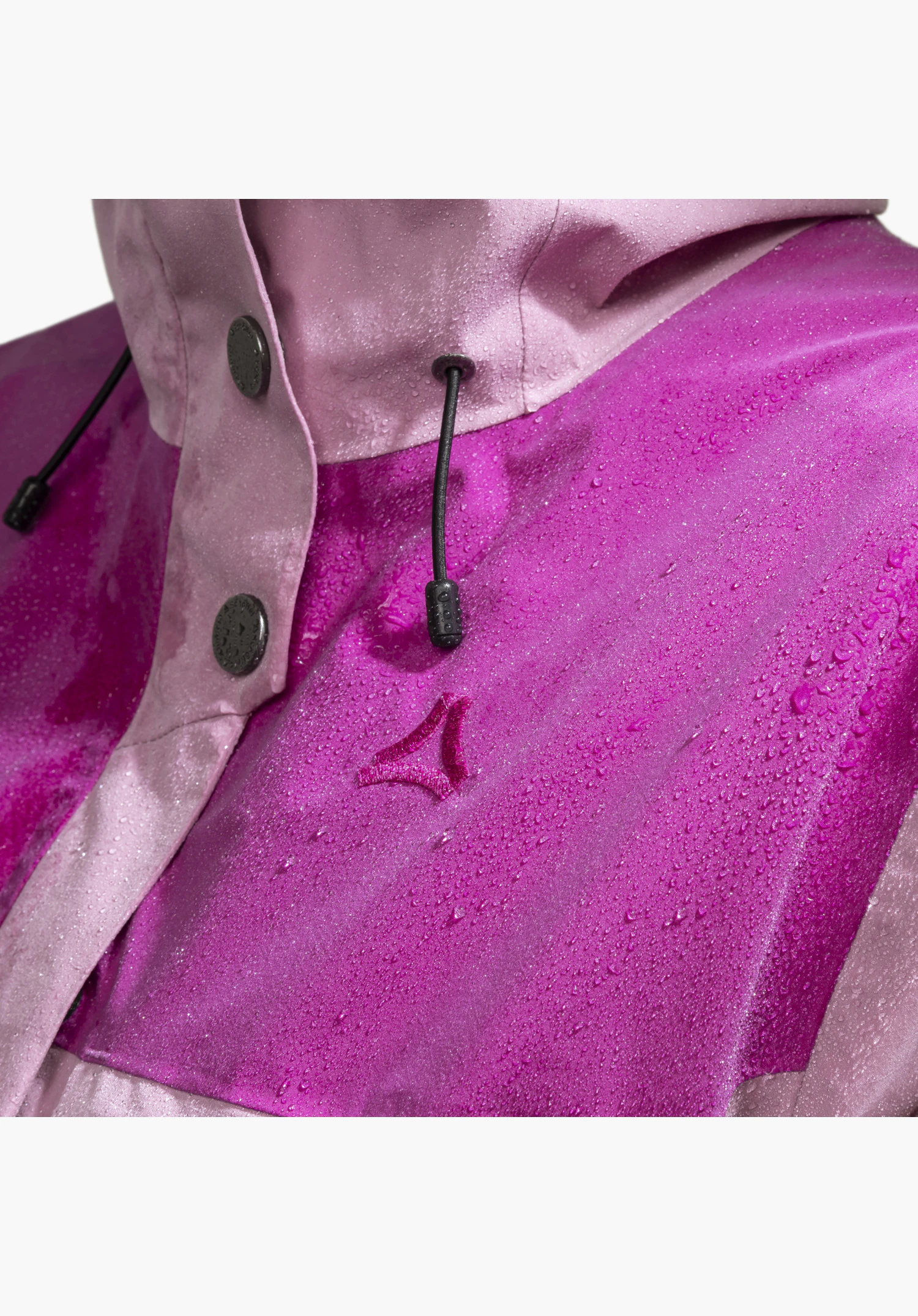 2L Jacket Style Maghera WMN zeigt das gestickte Schöffel-Logo auf dem wasserabweisenden rosa Stoff mit Wassertropfen, kombiniert mit einer Knopfleiste mit dunklen Druckknöpfen und einem Kordelzug als Nahaufnahme vor weißem/neutralem Hintergrund.