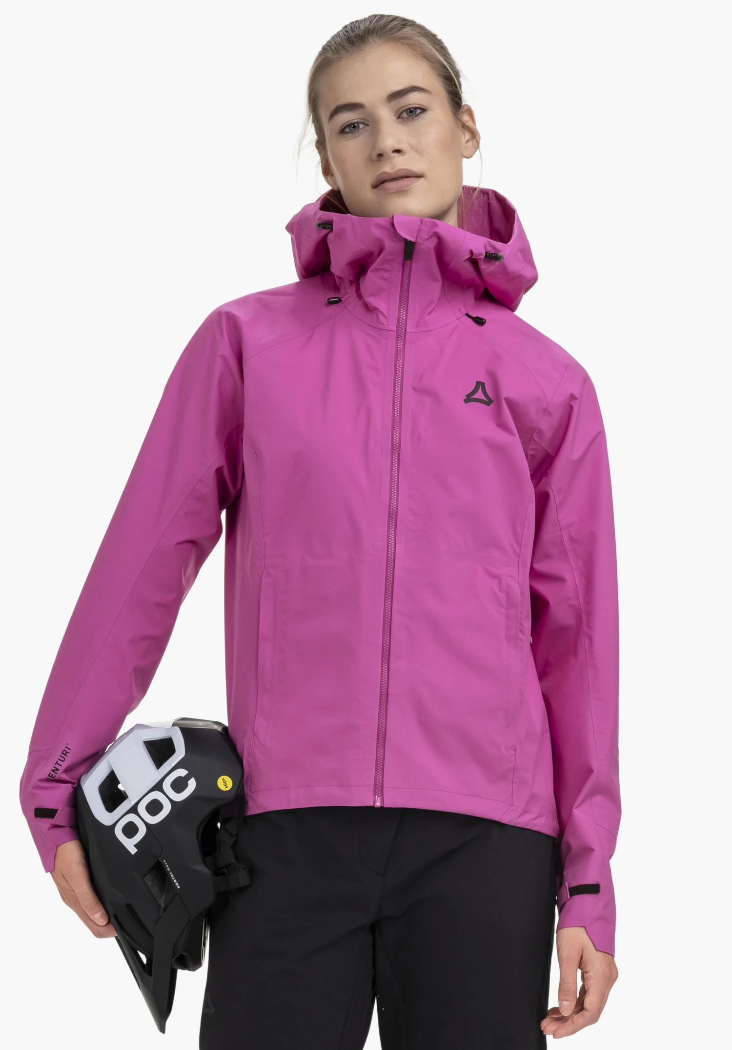2.5L Jacket Style Tajiva WMN on a model standing facing forward and holding a bicycle helmet under her right arm. The pink jacket features a closed zip and the Schöffel logo on the left chest, presented in front of a neutral background.