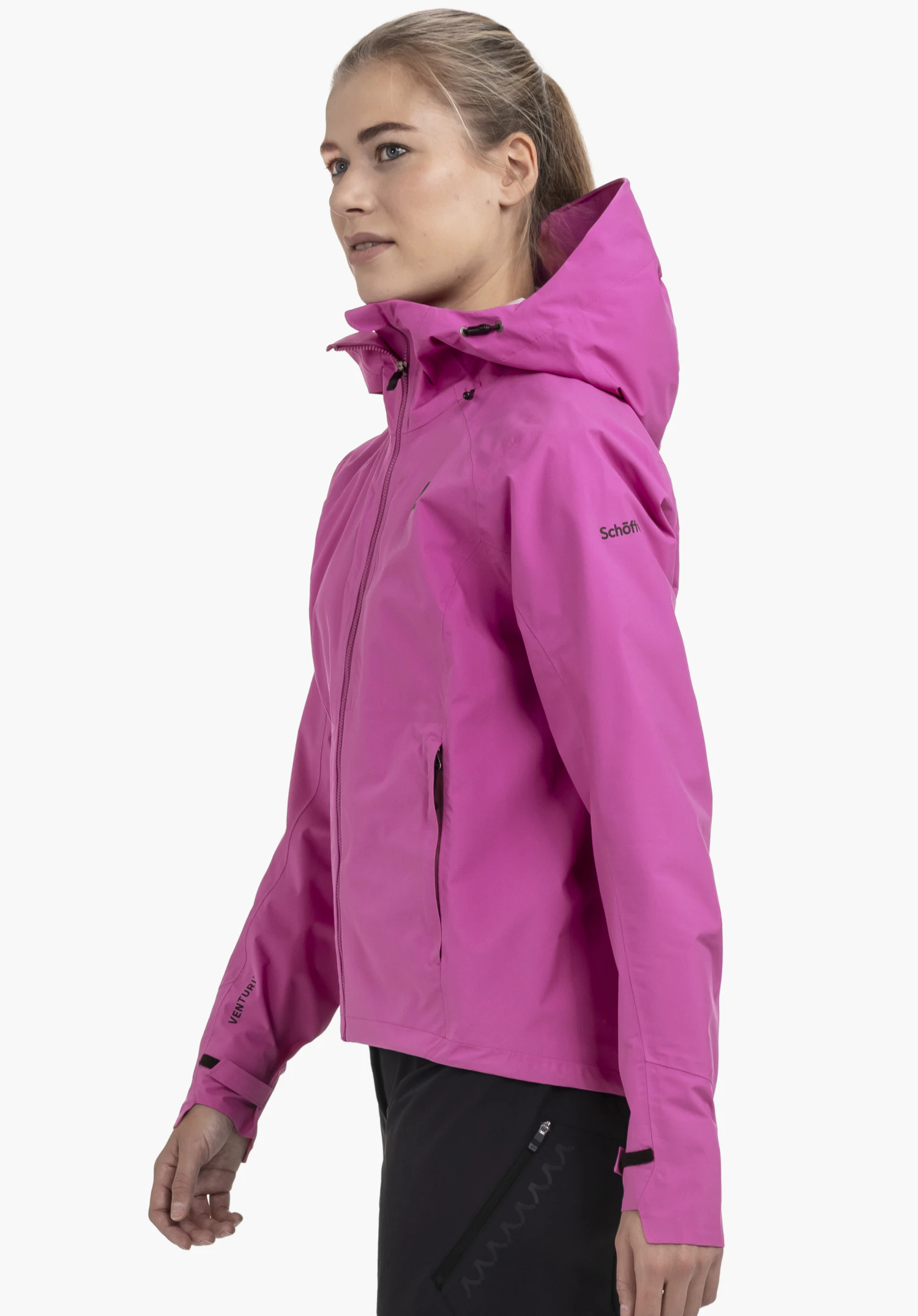 2.5L Jacket Style Tajiva WMN in leuchtendem Pink: Das Model steht seitlich vor einem neutralen Hintergrund und präsentiert die Passform der Jacke. Das dezente Schöffel-Logo auf dem Oberarm unterstreicht den sportlichen Look.