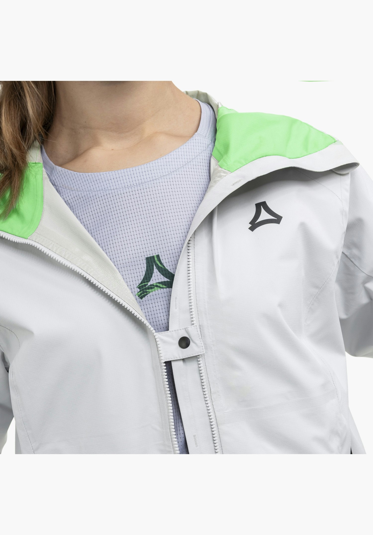 2.5L Jacket Style Tajiva WMN showing the partially opened front zip with a popper fastening tab, the grey fabric, the black Schöffel-Logo on the chest and the bright green inner lining at the collar, as a close-up against a white background.