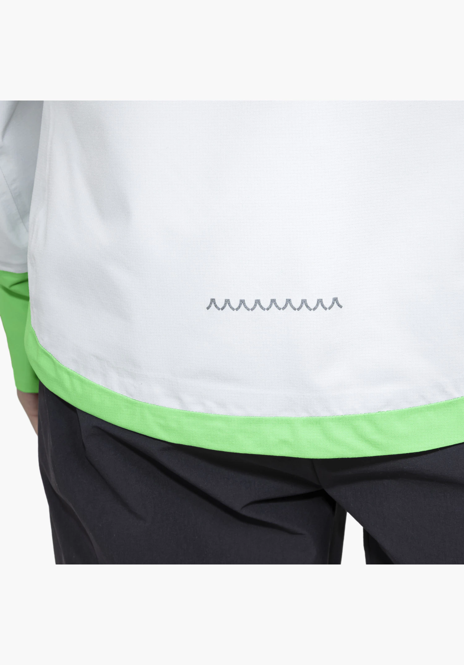 2.5L Jacket Style Tajiva WMN, vue détaillée du tissu gris clair dans le bas du dos avec un ourlet vert vif et un motif imprimé de sommets montagneux gris foncé, gros plan sur fond blanc/neutre.