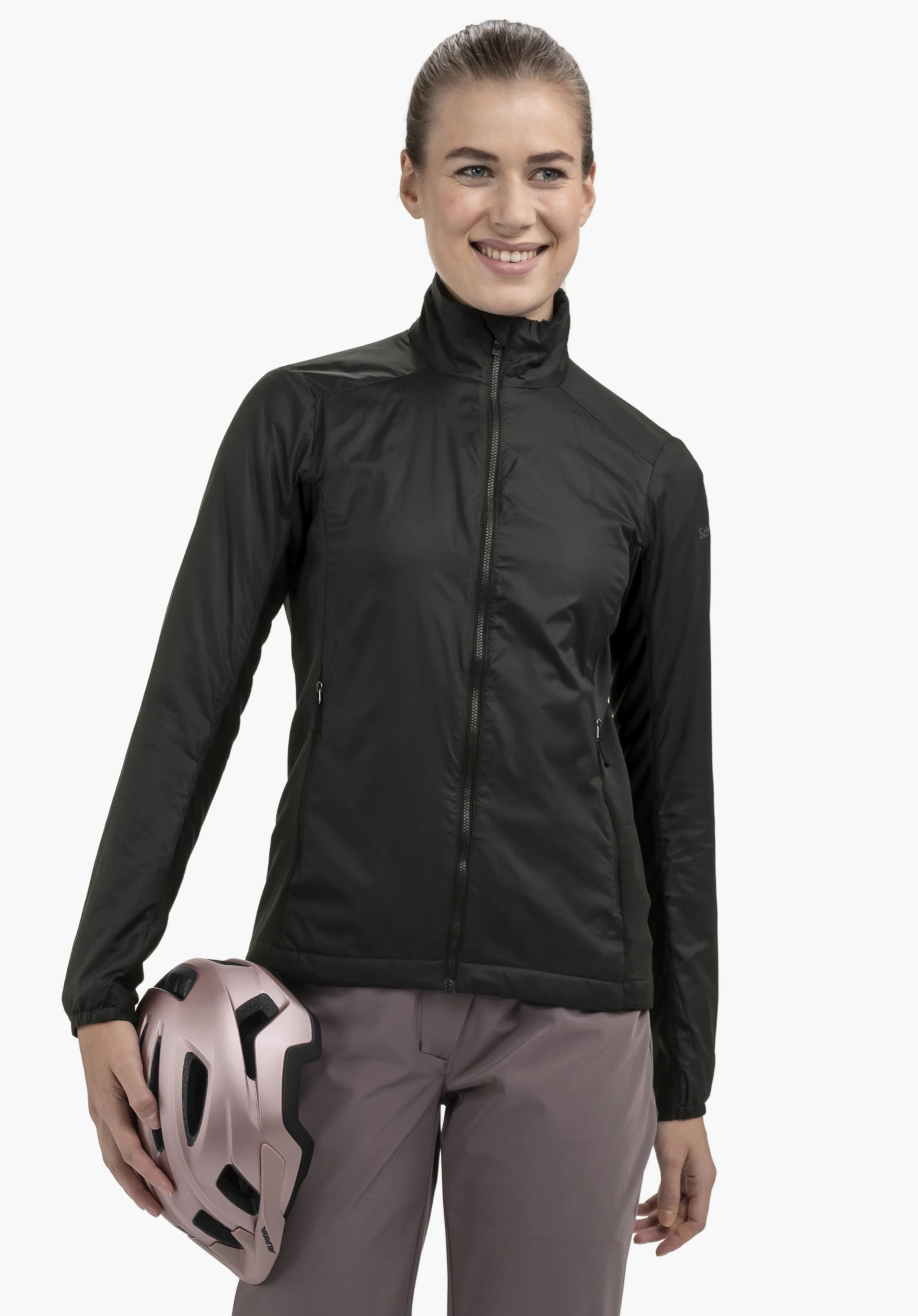 Ins Jacket Style Samaia WMN in black on a model. The woman stands facing the front and holds a bicycle helmet under her right arm, with the Schöffel logo visible on the left sleeve, presented against a neutral background.
