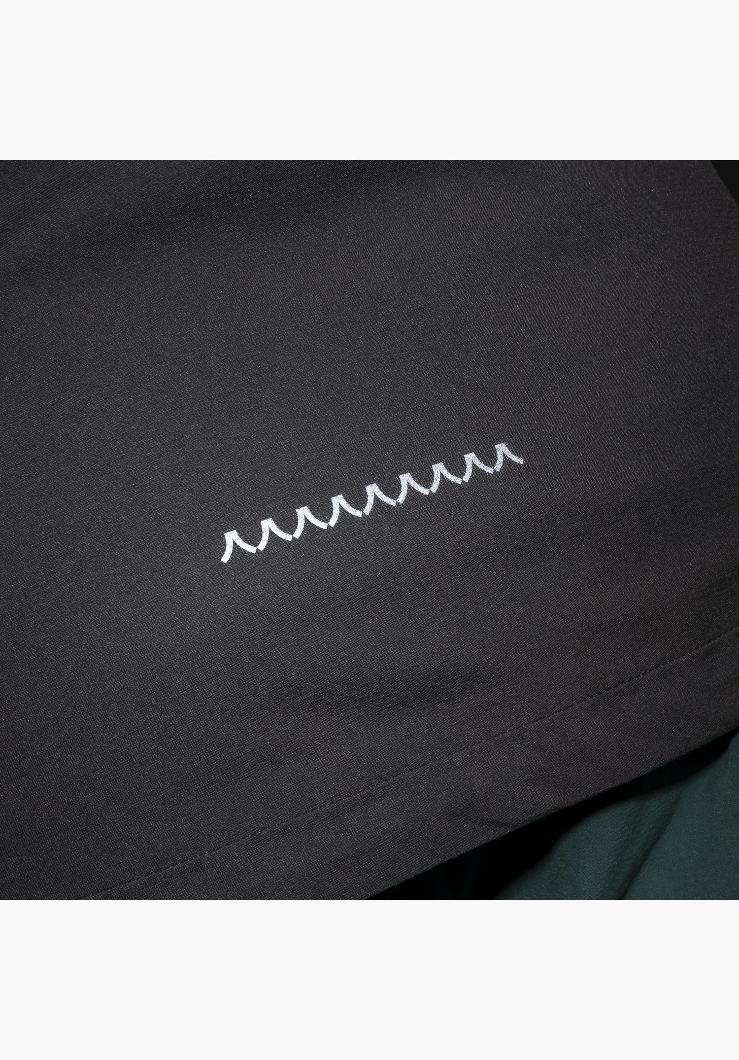 2.5L Jacket Style Tajiva MEN, detail of the white Schöffel logo on the black fabric, close-up against a white/neutral background.