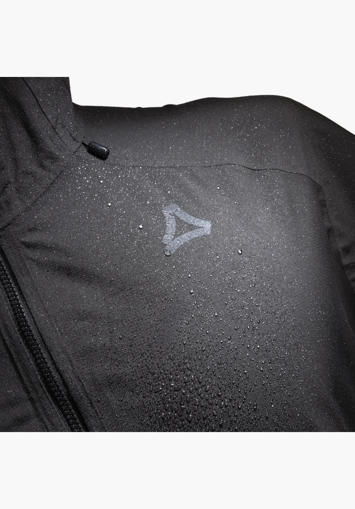 2.5L Jacket Style Tajiva MEN, black fabric with beading water droplets, the Schöffel-Logo and a partial zip as a close-up against a white background.