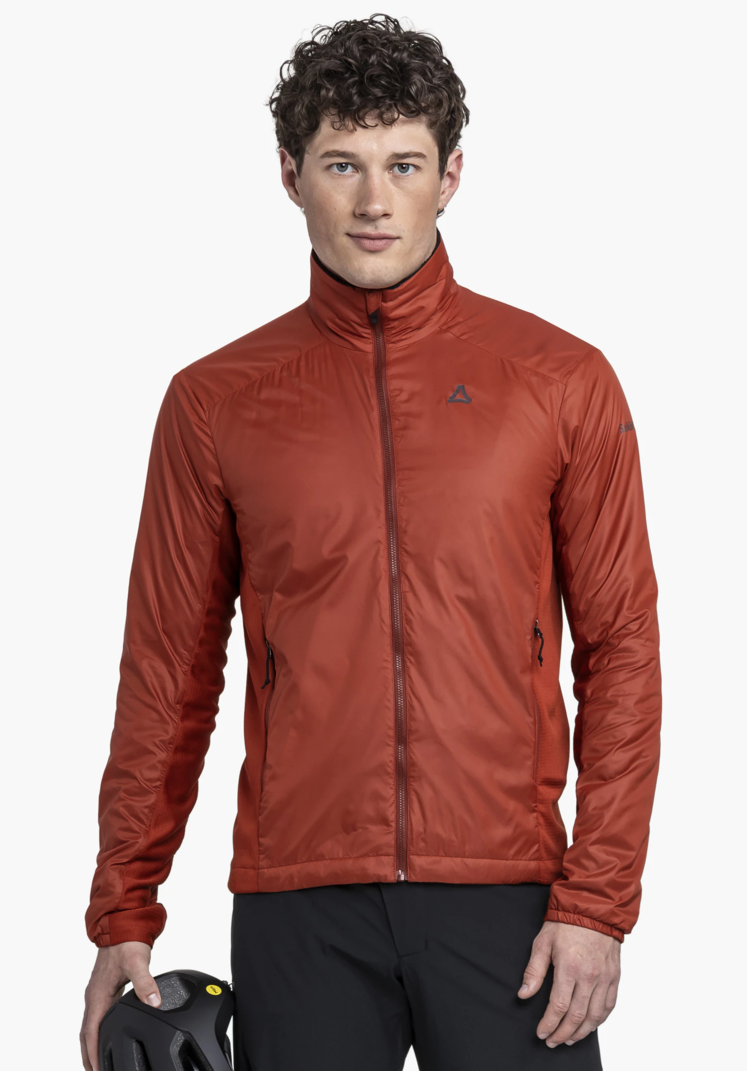 Ins Jacket Style Samaia MEN en rouge. Un mannequin se tient de face et porte la veste fermée avec le Schöffel-Logo visible sur la poitrine gauche, tenant un casque à la main, devant un fond neutre.