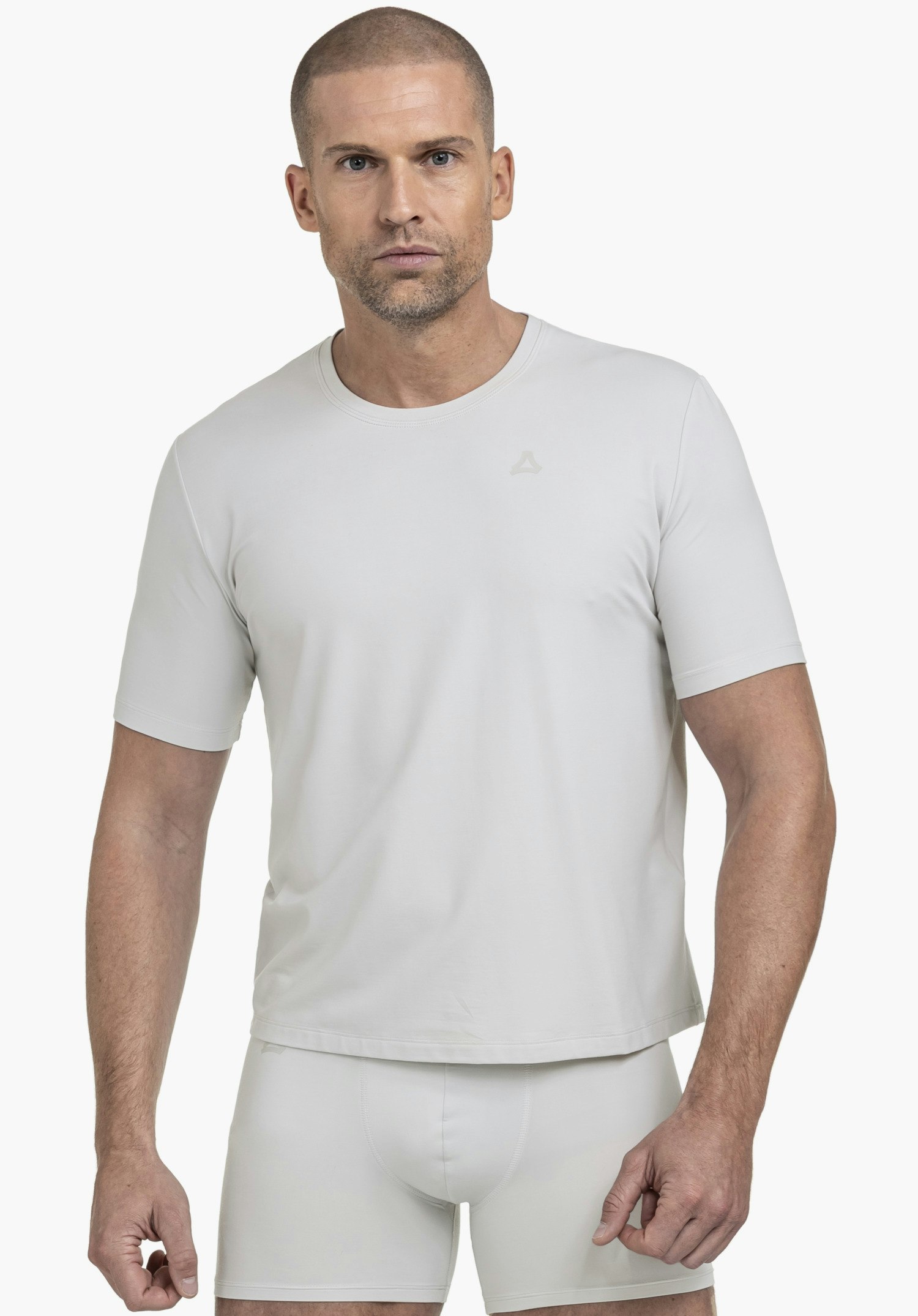 T Shirt Style Mafadi MEN. Ein Model steht frontal und trägt das graue T-Shirt mit dem Schöffel-Logo auf der linken Brust vor einem neutralen Hintergrund.