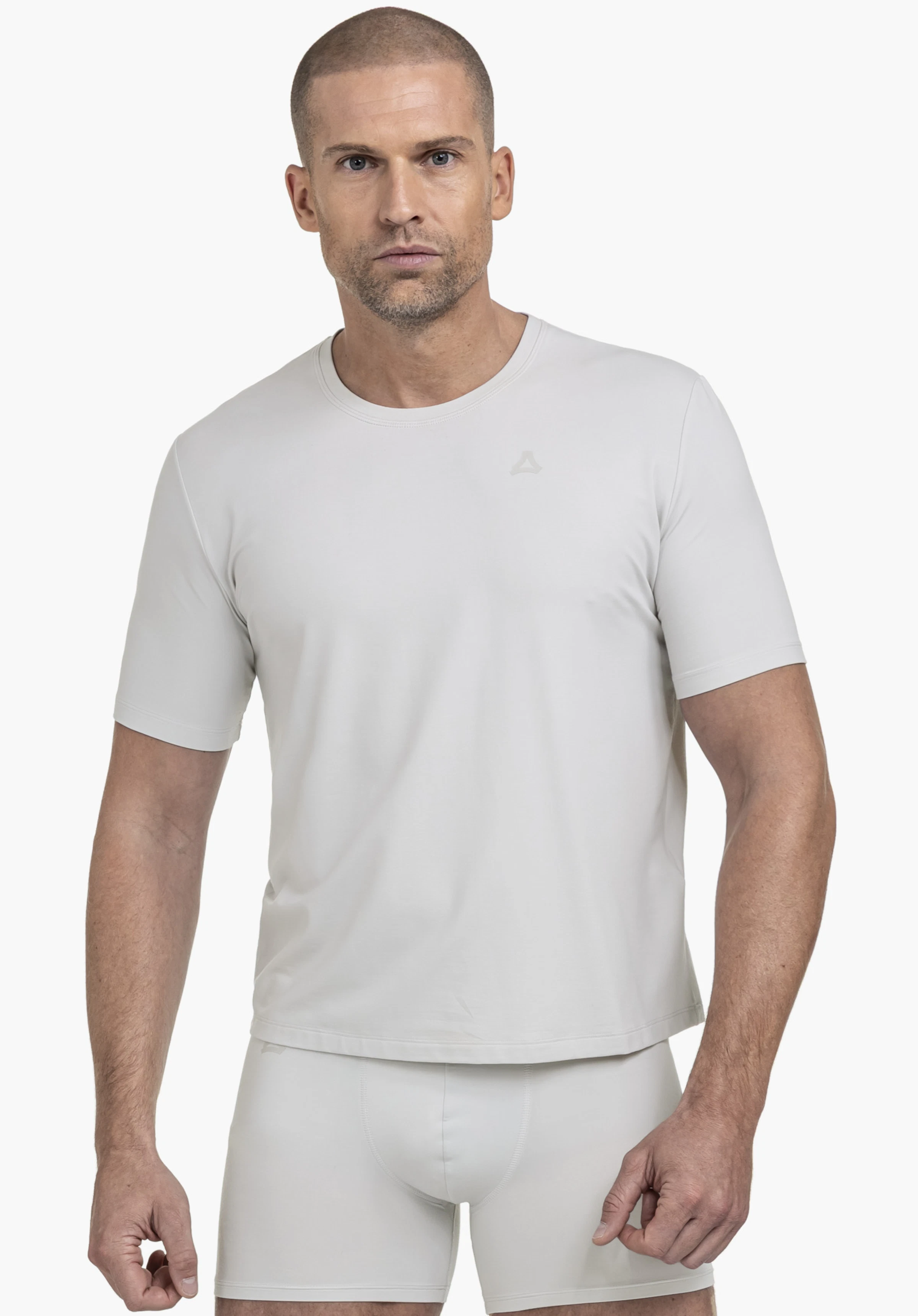 T Shirt Style Mafadi MEN. Ein Model steht frontal und trägt das graue T-Shirt mit dem Schöffel-Logo auf der linken Brust vor einem neutralen Hintergrund.