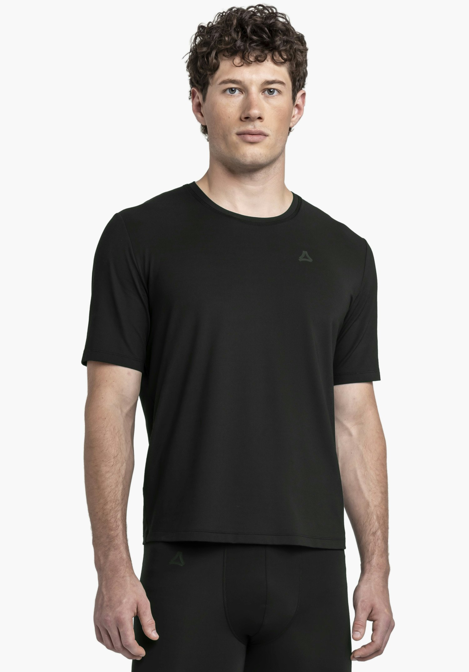 T Shirt Style Mafadi MEN. Ein Model steht frontal und trägt das schwarze T-Shirt mit dem Schöffel-Logo auf der linken Brust vor einem neutralen Hintergrund.