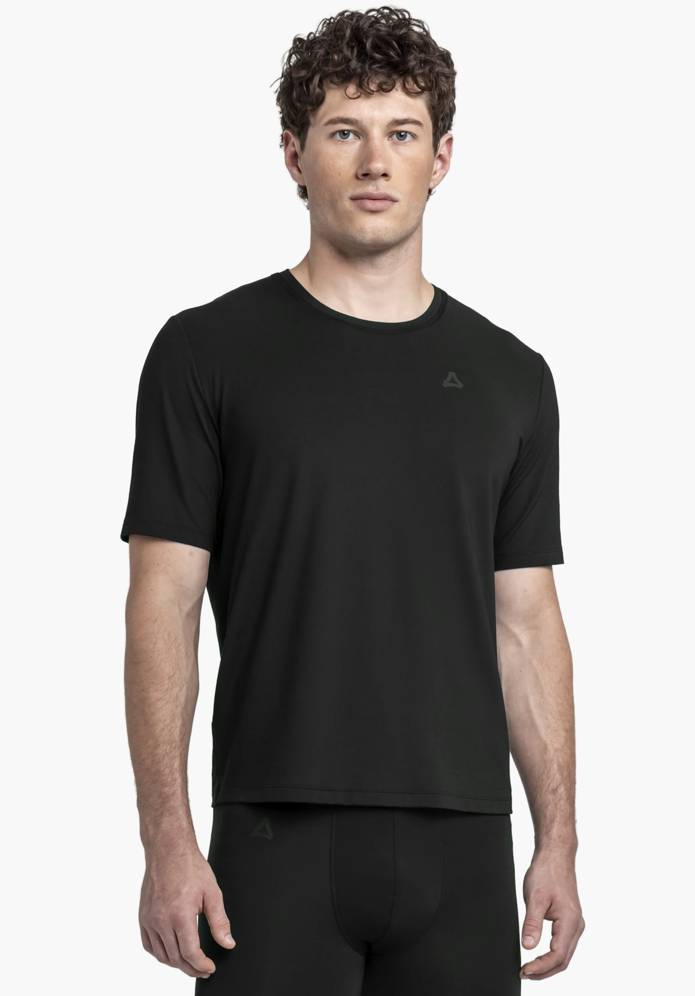 T Shirt Style Mafadi MEN. Ein Model steht frontal und trägt das schwarze T-Shirt mit dem Schöffel-Logo auf der linken Brust vor einem neutralen Hintergrund.
