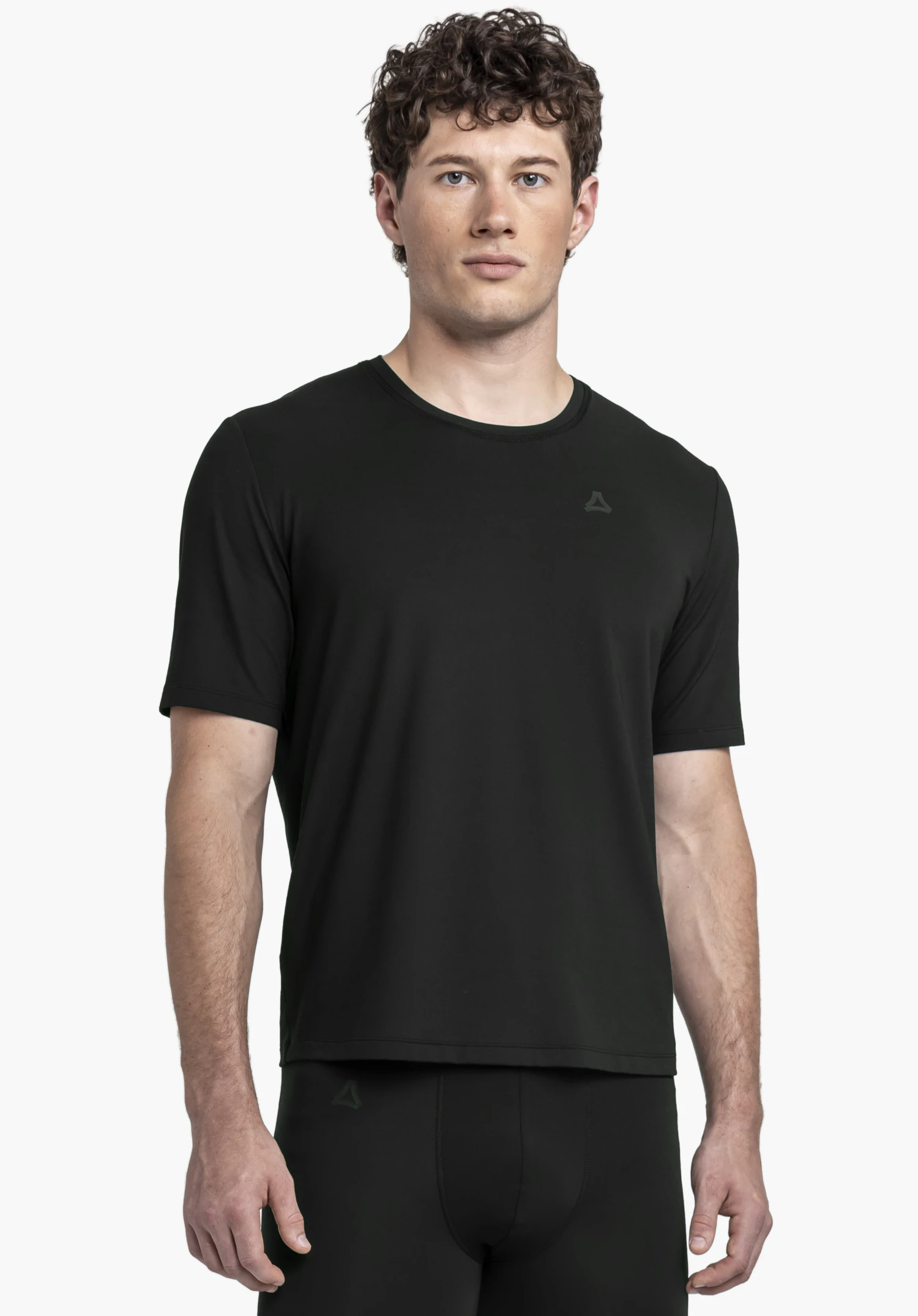 T Shirt Style Mafadi MEN. Ein Model steht frontal und trägt das schwarze T-Shirt mit dem Schöffel-Logo auf der linken Brust vor einem neutralen Hintergrund.