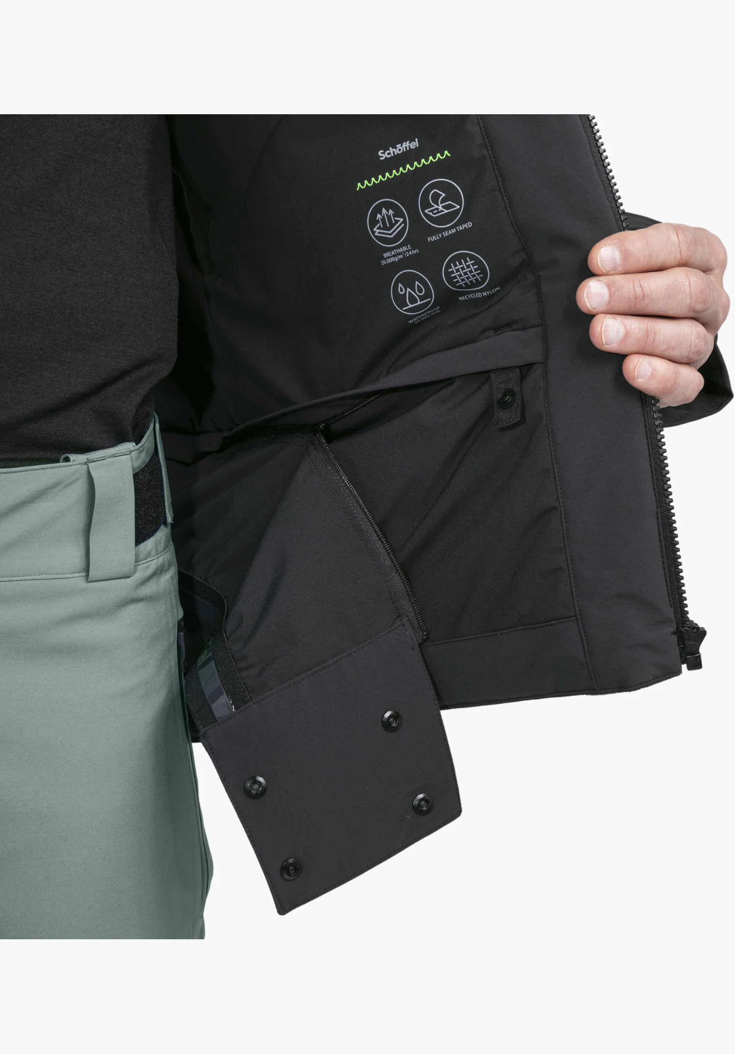 Jacket Style Radiana MEN in black showing the interior with the white Schöffel logo, functional icons, and the integrated snow guard with snap buttons and zipper, close-up against a white background.