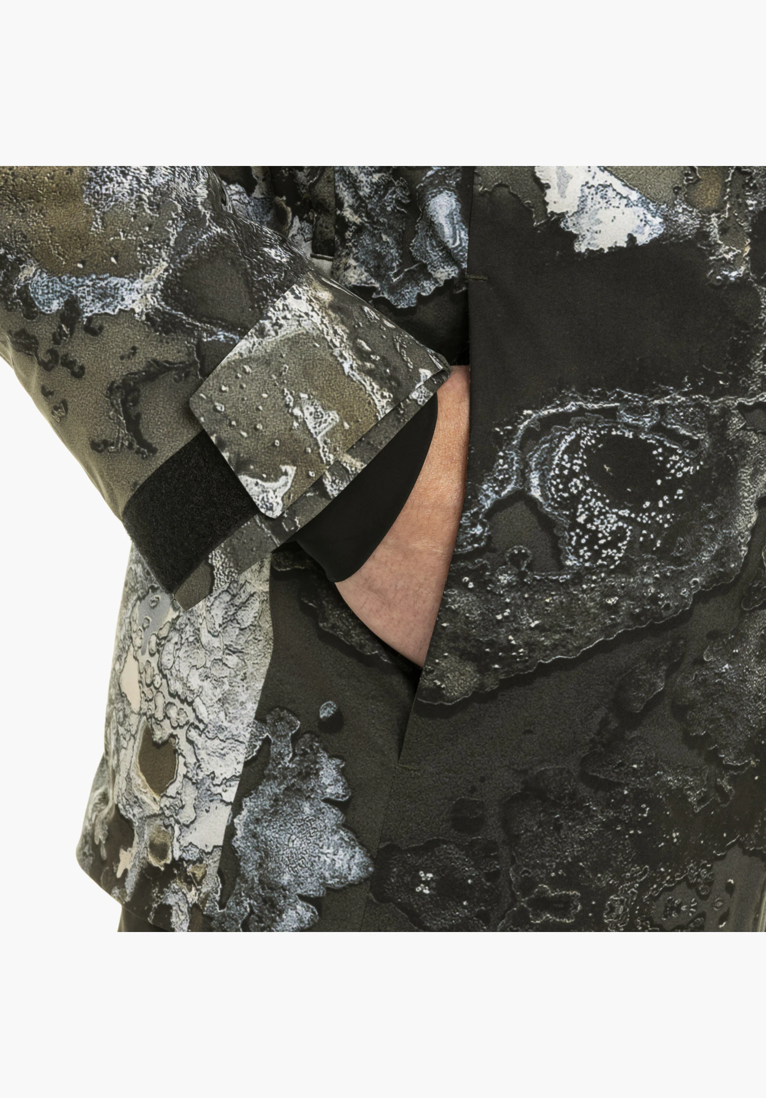 Schöffel X Tom Hegen JK MEN detail view of the green cuff with velcro fastening and the practical slip pocket with hand close-up against a white background.