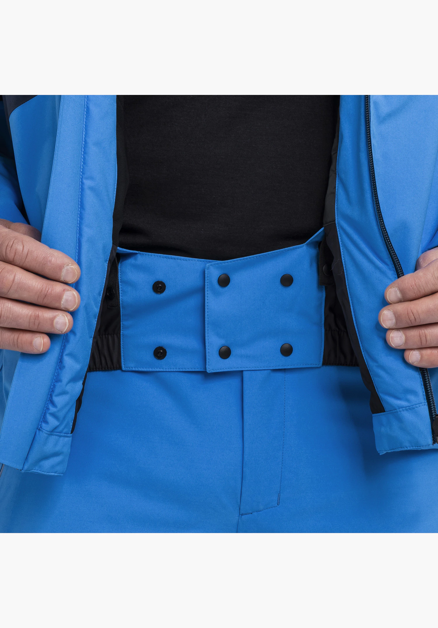 Jacket Style Trifex MEN en bleu avec un focus sur la jupe pare-neige intégrée avec des boutons-pression à la taille gros plan sur fond blanc.