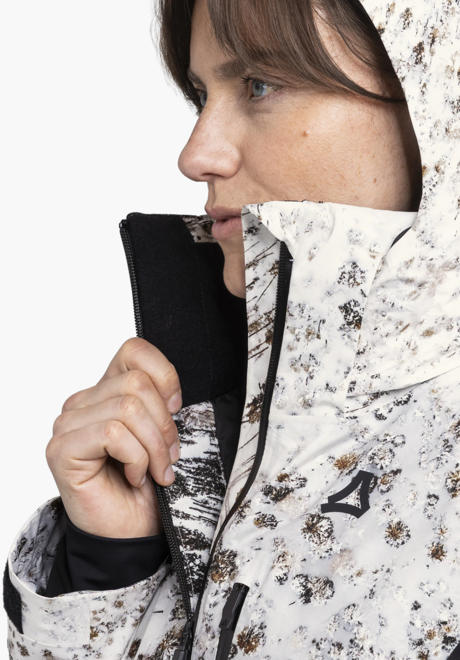 Schöffel X Tom Hegen JK WMN en couleur nature, porté par un mannequin femme en vue de profil avec un col montant, une capuche et le logo Schöffel visible sur fond blanc. (Généré par IA)