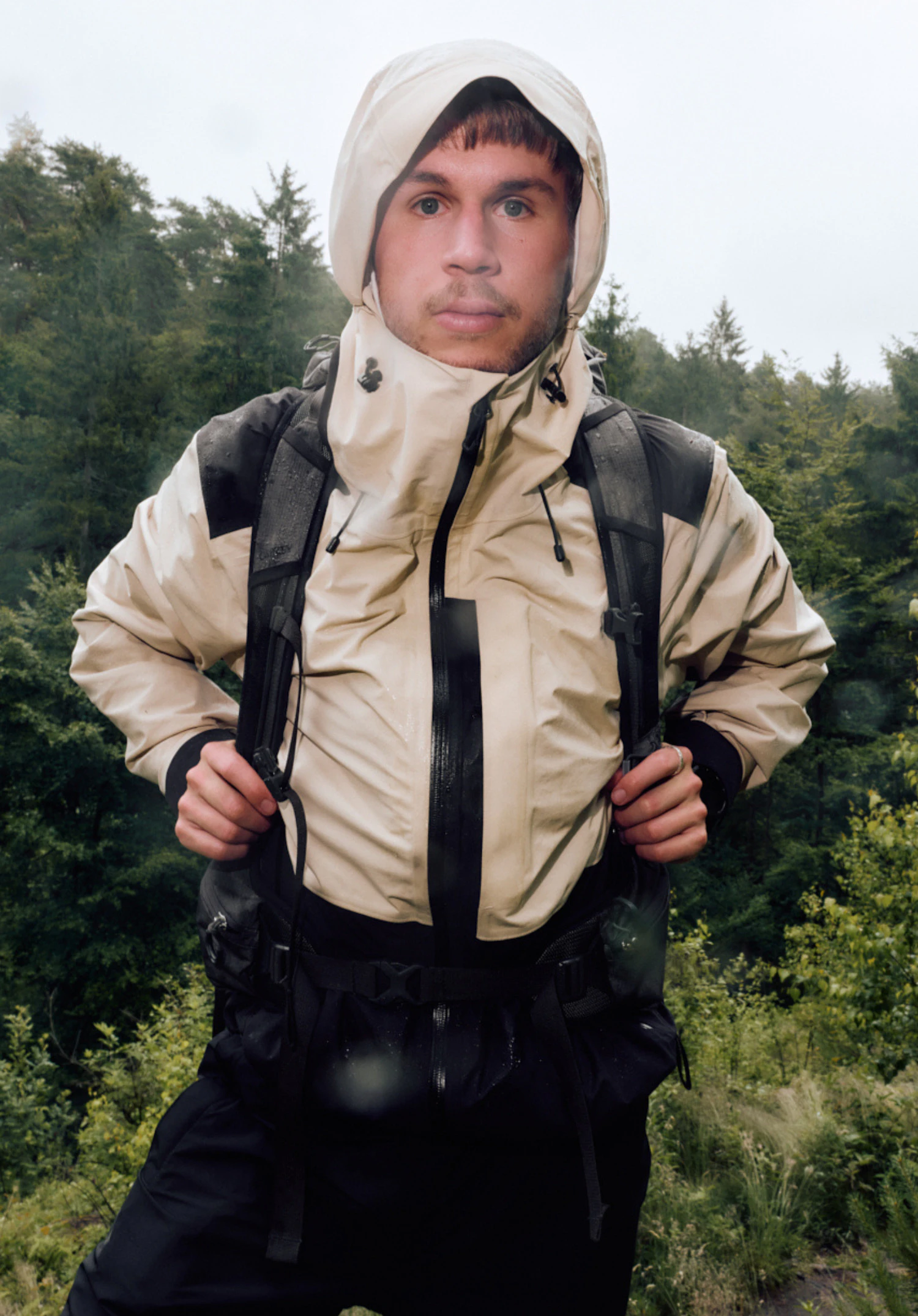 2L Jacket Style Refoca MEN in beige with black colour blocking, worn by a male model standing upright and shown from the front with arms hanging down and the hood closed against a white background. (AI-generated)