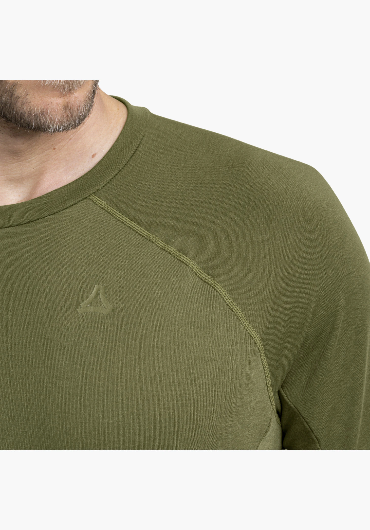 Longsleeve Style Refoca MEN in green showing a close-up of the shoulder area with tonal raglan seams and the subtle Schöffel logo on the right chest in a close-up against a white background.