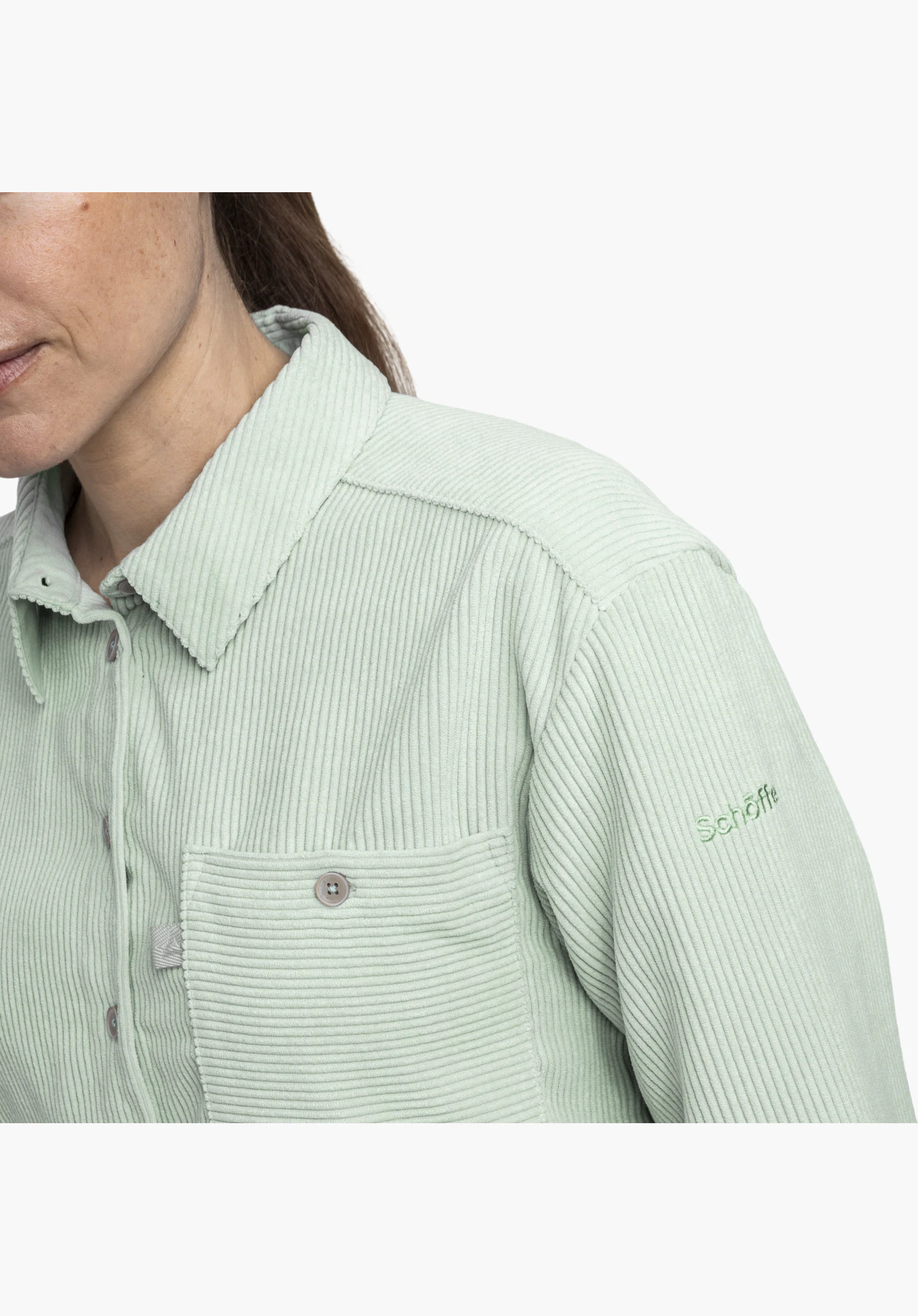 Blouse Style Libereo WMN in groen toont de corduroy materiaalstructuur, kraag, borstzak met knoop en geborduurde Schöffel-tekst op de linkermaal in een close-up tegen een witte achtergrond.